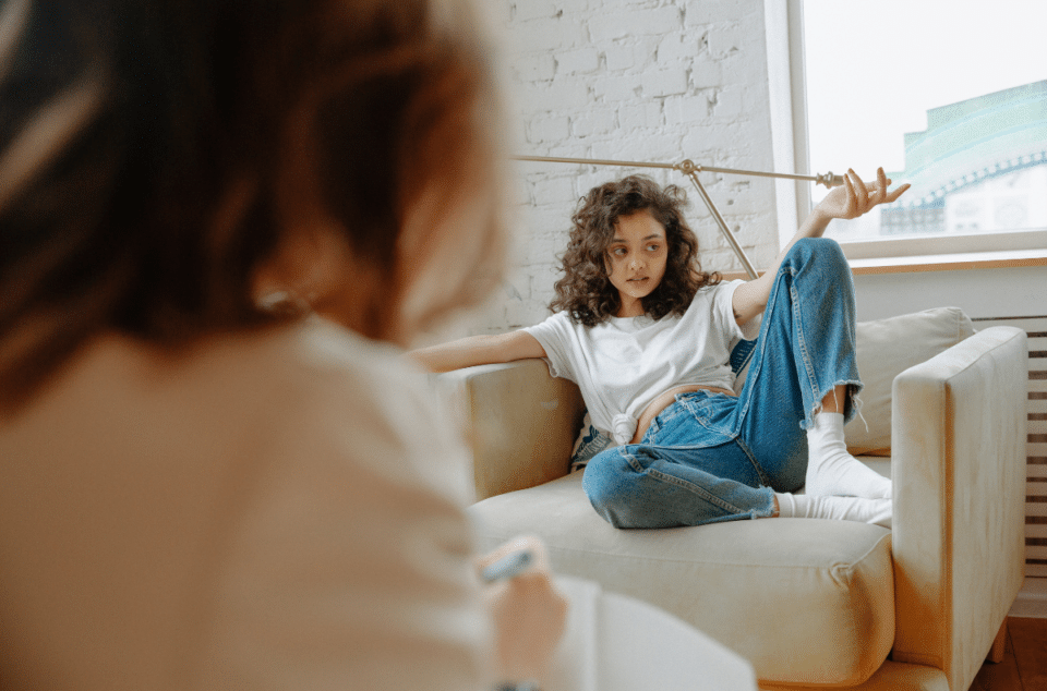 a girl receiving eating disorder treatment with autism, sitting on a couch talking to a therapist