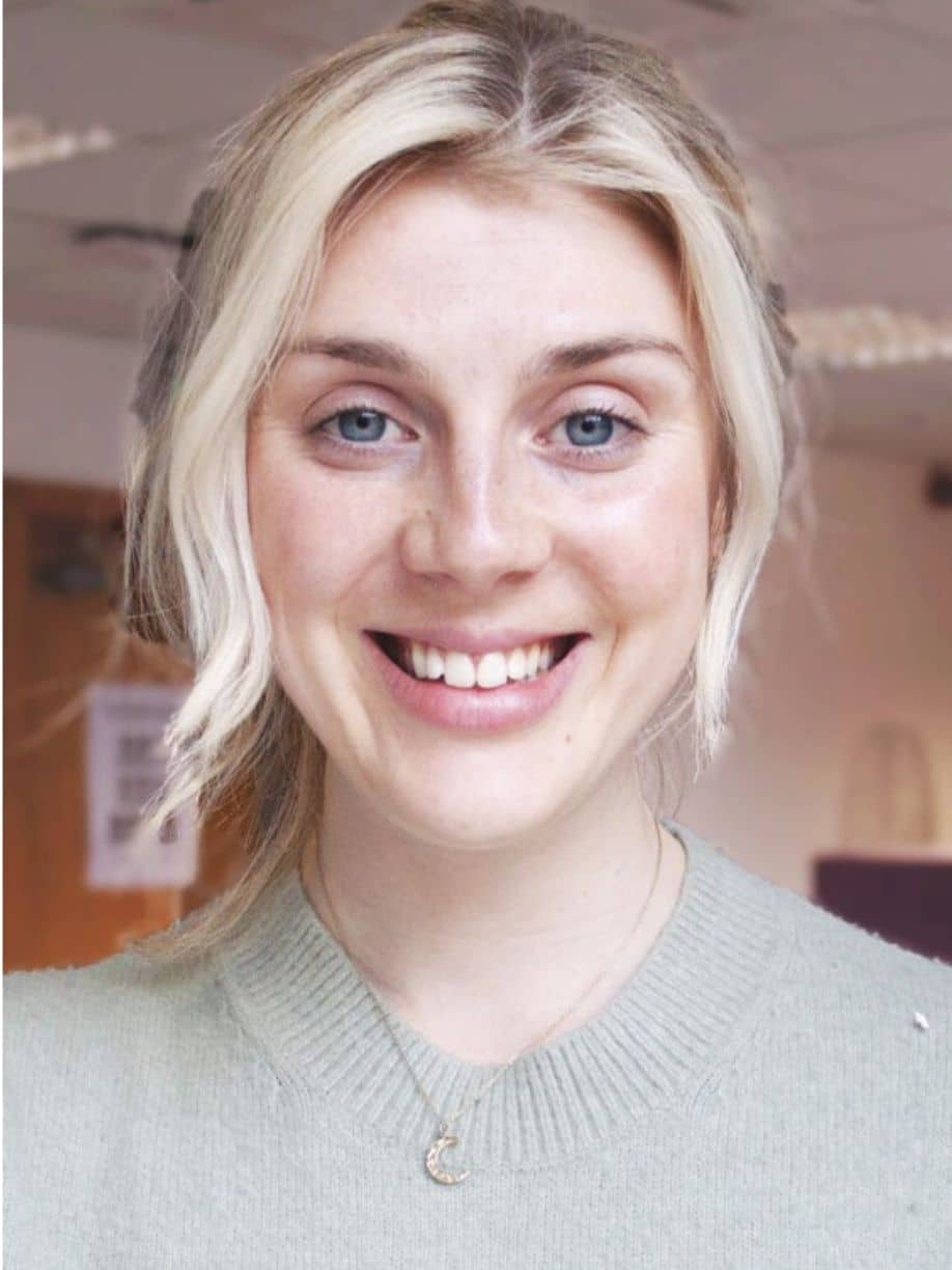 Iona Gillies is a trainee psychologist. She has blonde hair and blue eyes wearing a green sweater, smiling at the camera.